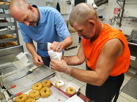 Quinn Jacobs helps a Special Olympics Alberta athlete make a Tim Hortons donut.