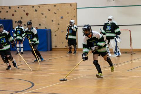 Thien running up the gym floor with the puck on his hockey stick