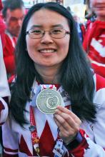 Susan Wang outdoors holding her 2017 World Games bronze medal and smiling