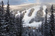 Bird's eye view of Sun Peaks resort with mountains of snow and resort buildings in background